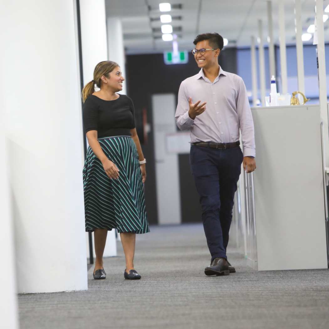 Two DXC employees walking through open-plan office, Human experience management | DXC Technology
